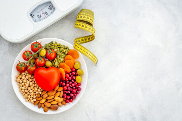 Heart shaped dish of fruits and healthy food with weight scale