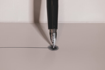 silver fountain pen vertical on a white background making a line