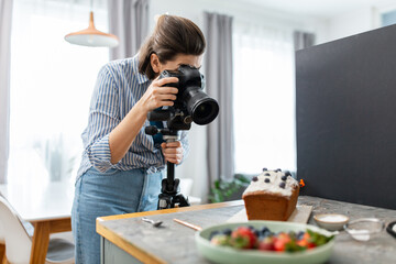 blogging, profession and people concept - happy smiling female food photographer with camera photographing cake in kitchen at home