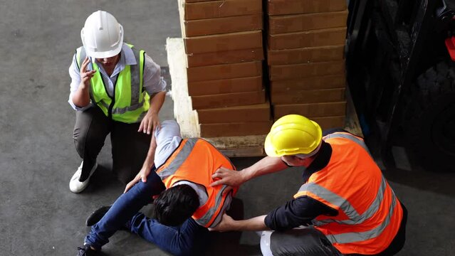 Top view. First Aid and safety first. Engineering talking on walki talki radio to employee while his warehouse coworker lying unconscious at industrial factory. Health insurance emergency accident.