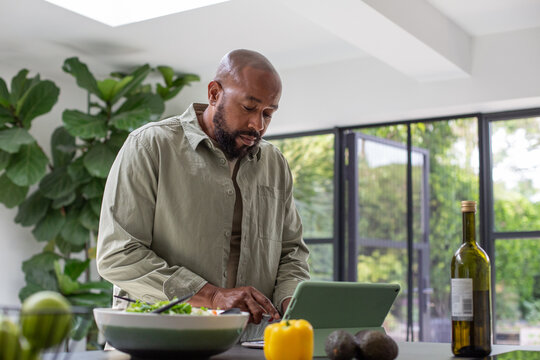 Mature Black Male Preparing A Healthy Meal Using A Digital Tablet