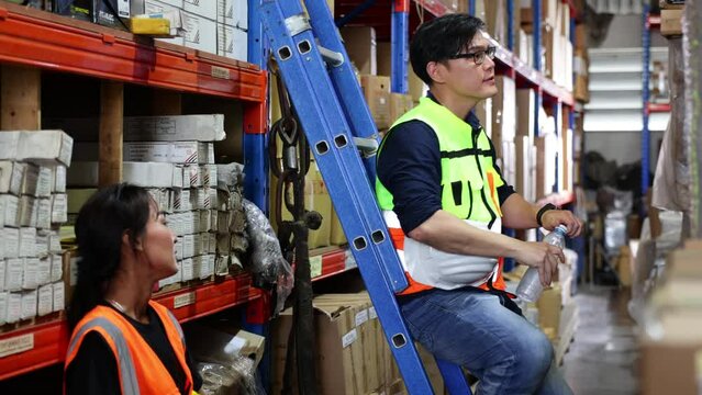 Time for a tea break concept. Asian male and female warehouse Industrial factory energy engineer drinking water sitting on stair warehouse office factory workplace. Professional engineer team working.