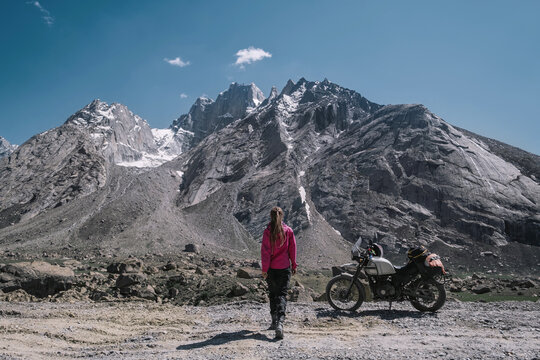 Female motorcyclist in dangerous off-road trip in the mountains with her motorcycle against the backdrop of stunning high mountain