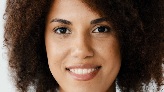 Front view female smiling toothy perfect dark skin natural make-up face. Close up African American curly woman girlfriend biracial lady look at camera open and confident smile with healthy white teeth