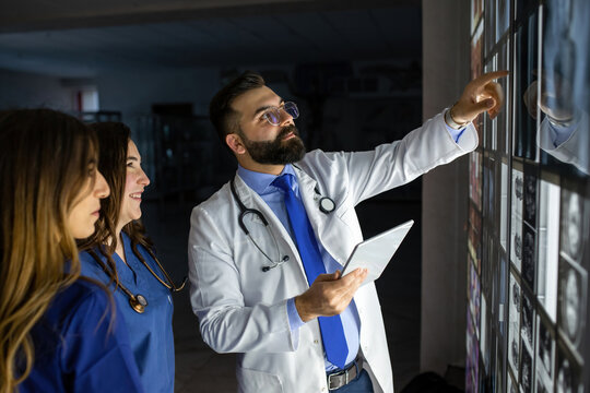 A group of surgeon interns is studying fetal development at different stages of pregnancy. Health education concept. Medical students in the classroom with images of ultrasound