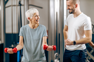 Fototapeta na wymiar Senior Woman Doing Workout With Coach In The Gym