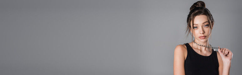 pretty woman with makeup touching silver necklace isolated on grey, banner