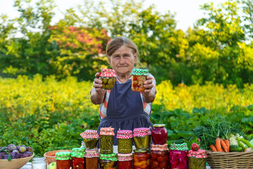 Senior woman preserving vegetables in jars. Selective focus.