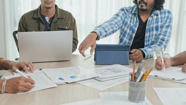 Cropped slowmo of unrecognizable male marketing specialists analyzing statistics and signing business documents while sitting at office desk having meeting