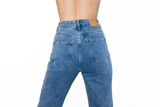 Stylish blue jeans with a high fit on a slender young woman standing with her back isolated on a white background. Rear view. Fashion concept