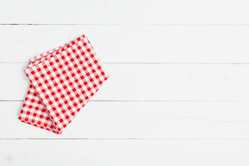 The tablecloth checkered red and white fabric cotton folded place on a white table with copy space. Top view fabric tablecloth on old white wood background. Flat lay checked fabric old wooden.
