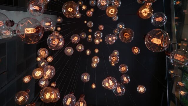 Beautiful loft-style chandelier on a dark ceiling background. A large loft-style chandelier with light bulbs at different heights. High quality FullHD footage