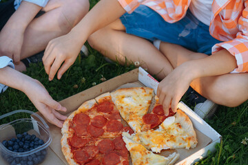 children having lunch on grass after school. Kids hands grabbing slices of pizza