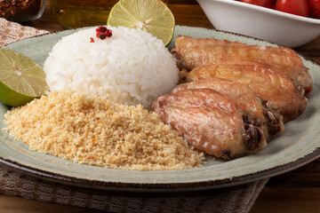 Grilled chicken wings served with rice and toasted manioc flour.