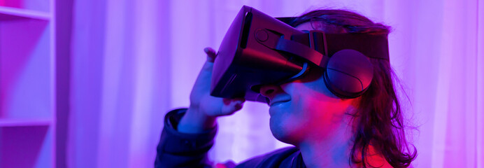 Man wearing virtual reality glasses is playing a 3D game with excitement, Bluetooth Remote Controller, VR, Future games, Gadgets, Technology, Red and blue background, VR game concept.