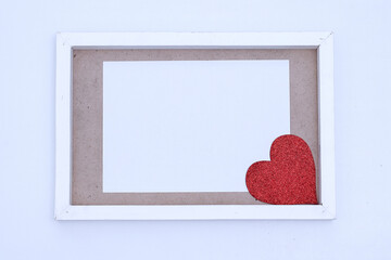 Blank white paper with red heart on a wooden frame. Mock-up of horizontal blank greeting card on white background. 