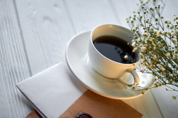 Top view cup of coffee and envelope with letter. Romantic breakfast with spring flowers.