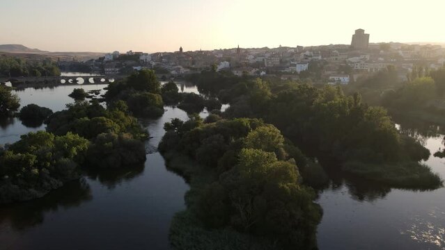 Medieval city on a hill and with the river at its feet in a golden sunset and clear sky with fog, Alba de Tormes, Salamanca.