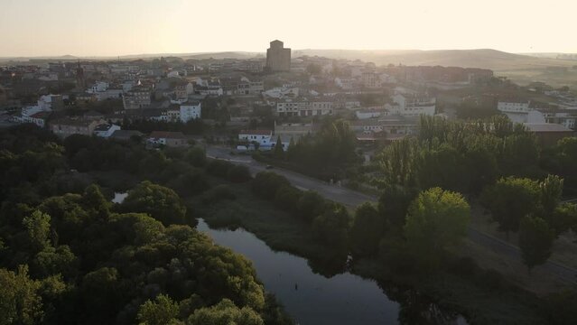 Medieval city on a hill and with the river at its feet in a golden sunset and clear sky with fog, Alba de Tormes, Salamanca.