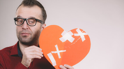 Thoughtful man holds broken heart