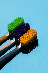 three toothbrushes (green, purple, orange) close up