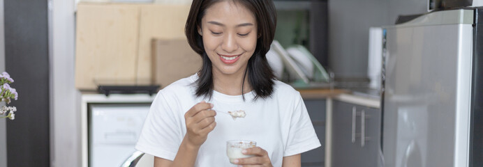 Fototapeta na wymiar Half-Japanese woman eats yoghurt with cereal for breakfast in room, Healthy food and digestive system maintenance, The most popular and easy to eat breakfast food.
