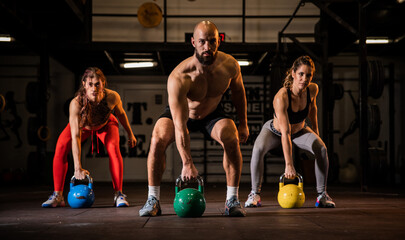 Fit group of people working out with weights together during an exercise class at a gym