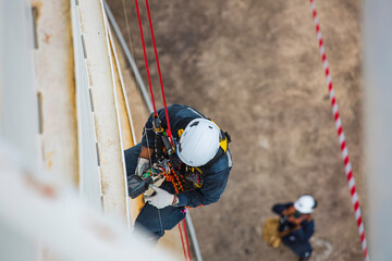 Top view male worker inspection wearing safety first harness rope safety line working at a high...