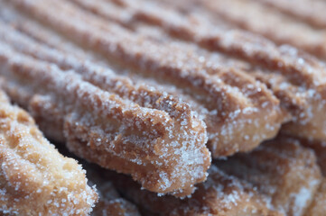 Nahaufnahme von süßen Churros. Ein sternförmiger frittierter Krapfen, welcher traditionell mit Zuckker oder Zimt angerichtet wird