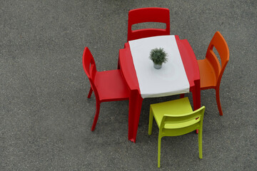 isolated deserted red cafe table and chairs on gray rustic floor view from above