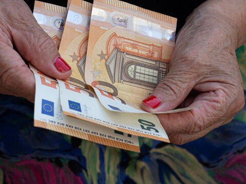 Woman's hands are holding a few euro coins. Pension, poverty, social problems and the theme of old age. Saving.