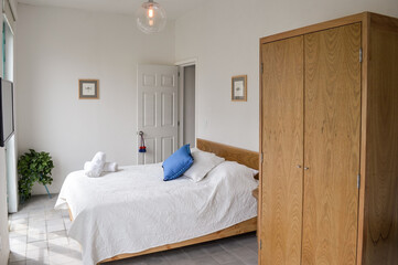 bed base, bedroom with mat on the floor, clay pot in the background, wooden credenza and mirror.