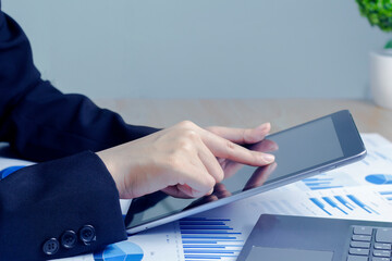 Close up hand of Business woman use devices tablet and laptop manage finances, analyze diagrams statistics in office.