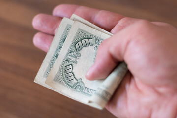 Mano sosteniendo billetes doblados de 100 dolares