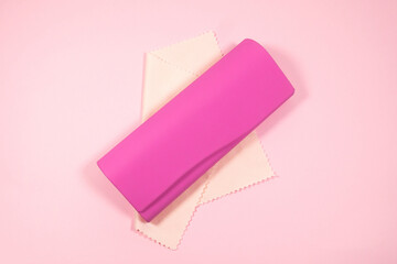 Pink frame womens glasses with glasses cleaning cloth and case on a pink background.