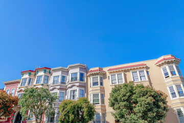 Fototapeta na wymiar Rowhouses with bay windows and apartment building with sash windows in San Francisco, CA