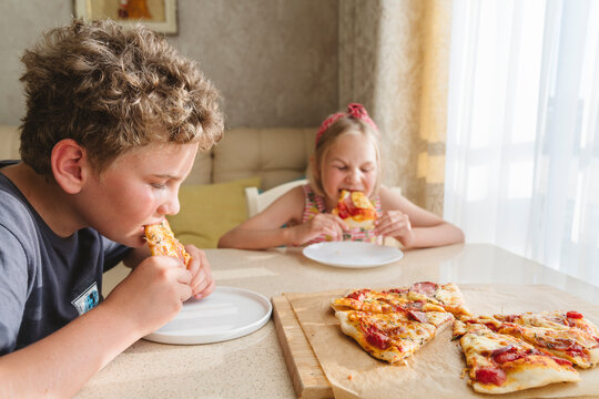Children eating homemade pizza at home.