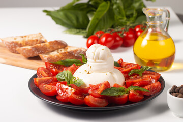 Traditional Italian burrata cheese with salad of delicious cherry tomato, basil leaves and olive oil.