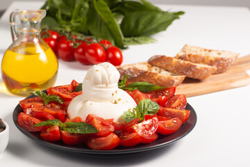 Traditional Italian burrata cheese with salad of delicious cherry tomato, basil leaves and olive oil.
