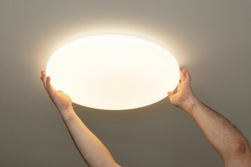 Glowing LED light fixture mounting with electrician hands