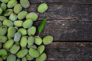 Green almonds background   fresh raw unripe wooden rustic table blurred garden background leaves, Top view concept with copy space shell  tree branch pattern texture