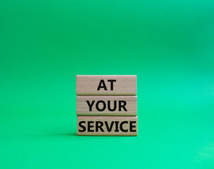 At your service symbol. Wooden blocks with words At your service. Beautiful green background. Business and At your service concept. Copy space.