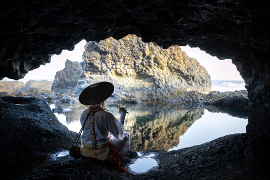 Shugendo monk is sitting in cave and meditating while looking at open sea