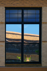 A window in an old yellow brick building reflecting another building