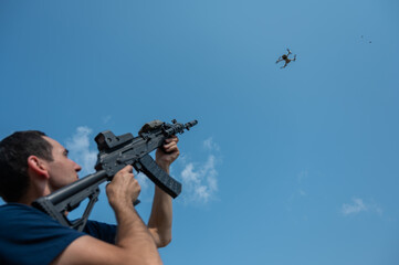 Caucasian man shoots a flying drone with a rifle.