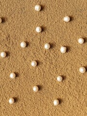Pearls pattern on the sand. A creative wedding concept with white pearl. Summer background with pearls on the sand.