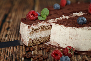 Sliced piece of tiramisu cake on wooden background