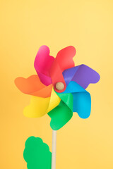 Coloured pinwheel on yellow background. Copy space. Vertical photo.