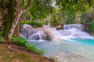 Magical turquoise blue colours of Kuang Si waterfalls Luang Prabang Laos. these waterfalls in the Mountains of Luang Prabang Laos flow all year round in the natural national park rainforest 