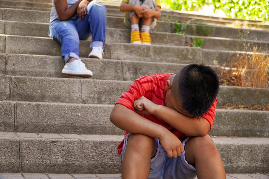 multiethnic children at school. bullying concept. child crying separated from the school children group